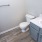 Renovated bathroom with white toilet and sink, accompanied by a gray cabinet